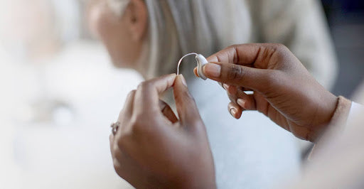 A person adjusting a hearing aid