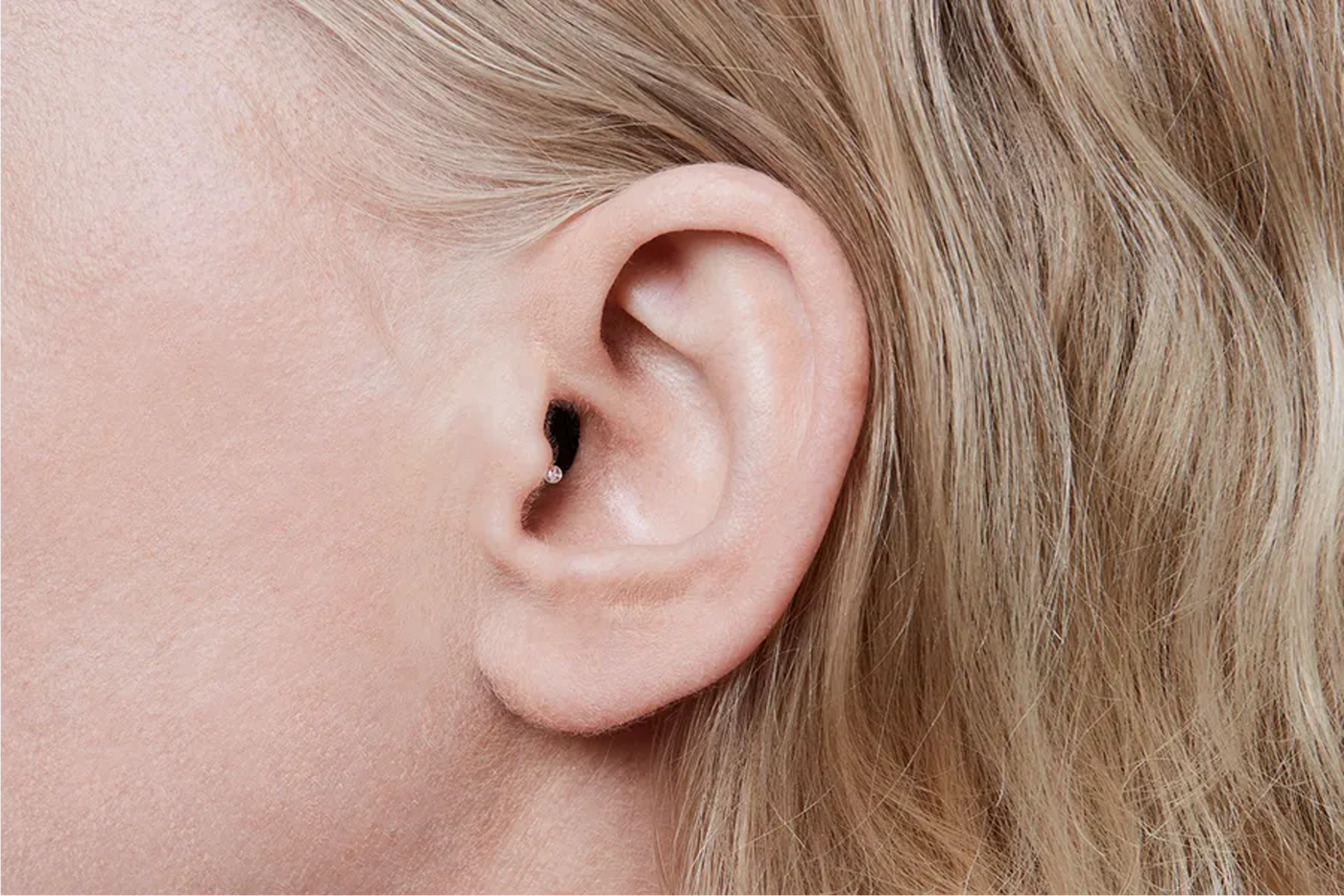A woman wearing the Oticon Opn IIC hearing aid.
