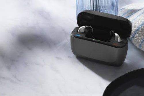 Beltone hearing aids in a sleek charging case on a table.