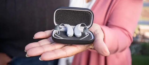 A person holding a case with Lexie Lumen hearing aids.